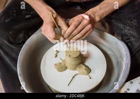 Close up view - professional potter shaping mug with special tool in workshop Stock Photo