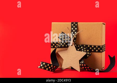 Gift box or present box with empty mock up tag, black golden ribbon on red background Stock Photo