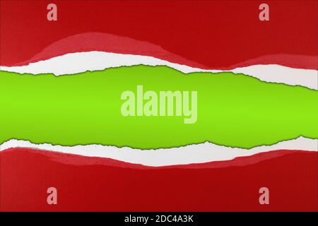 Hole ripped in red paper on green. Christmas background. Copy space Stock Photo