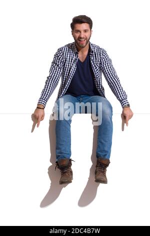 Smiling young woman in red lumberjack shirt, jeans and brown sneakers  sitting on a top and looking at camera. Full length studio shot isolated on  whit Stock Photo - Alamy