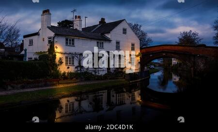 Bridgewater canal Lymm Moody clouds from day to dusk lights on the outside building Stock Photo
