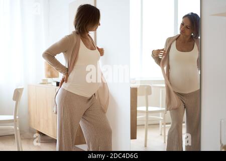 Healthcare, treatment. Young pregnant woman feeling sudden pain in her back. Future mom suffering from backpain. Stock Photo