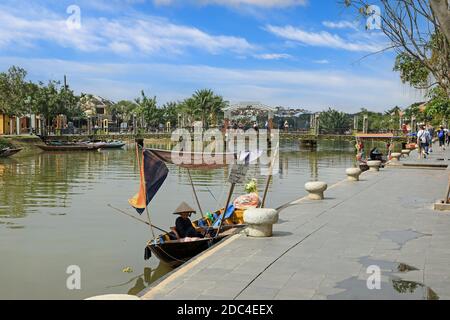 An old Vietnamese woman on a boat on the Thu Bon River with the Cau An Hoi Bridge in the background, Hoi An, Vietnam, Asia Stock Photo