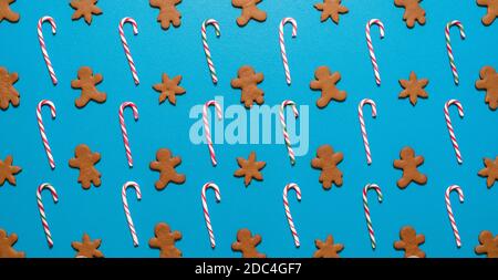 Top view with gingerbread cookies and striped lollipops symmetrically arranged on a blue-colored table. Homemade cookies and candy canes above view on Stock Photo