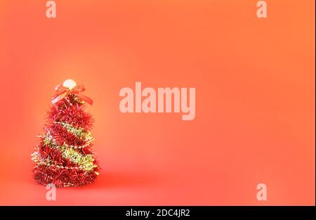 Christmas tree made of shiny bright decorative garland on red paper background Stock Photo