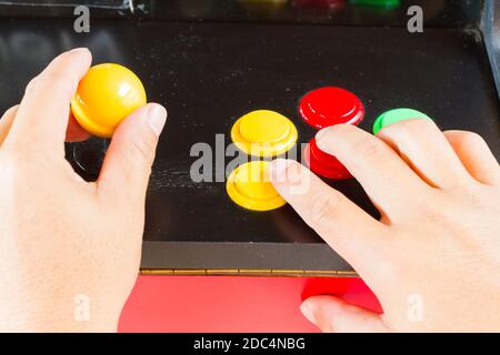 hands touching yellow joystick and buttons of old arcade video game Stock Photo