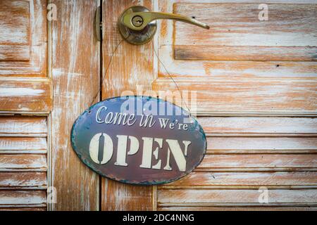 Come In We're Open on the wooden door, copyspace on the right. Stock Photo