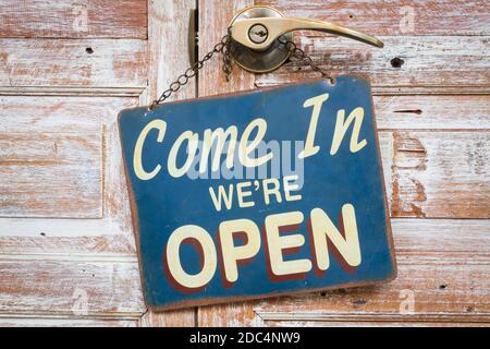 Come In We're Open on the wooden door, copyspace on the right. Stock Photo