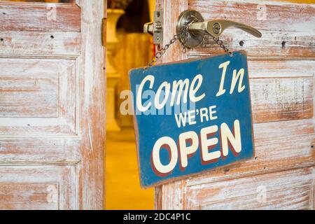 Come In We're Open on the wooden door open Stock Photo