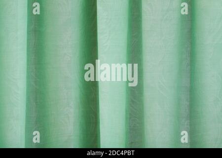 Close-up view of bright green curtain. Textured abstract backgrounds and wallpapers. Materials and textiles. Stock Photo