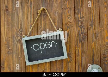 blackboard with the word open with rope on wooden door of a coffee shop. Stock Photo