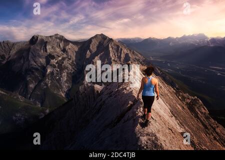 Adventurous Girl is hiking up a rocky mountain. Stock Photo