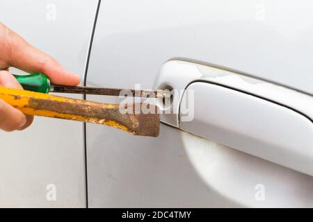 horizontal photo of closeup locksmith will open bronze car door white screwdriver - selective to focus on key hold. Stock Photo