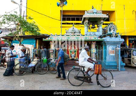 A man cycles past a small Hindu Temple next to the Jaffna bus station in Sri Lanka. Jaffna is the largest town in northern Sri Lanka. Stock Photo