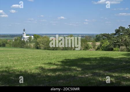 Polska, Poland, Polen, Europe, Greater Poland, Großpolen, Brzóstków; A vast spring landscape with a white church standing among fields and trees. Stock Photo