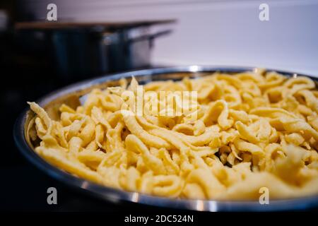 Close-up macro detail of fresh egg Alsatian homemade spaetzle in frying pan Stock Photo