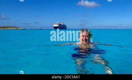 Half Moon Cay/Bahamas-10/31/19: A cruise ship happy cruise ship passenger having fun snorkeling with the cruise ship in the background. Stock Photo