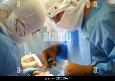Surgery. Surgeons in special sterile clothing perform surgical operation. Stock Photo