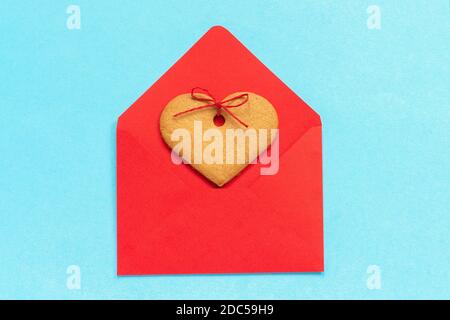 Red envelope and heart shaped ginger cookies close up on blue background. Top view Copy space Concept letter greetings with love