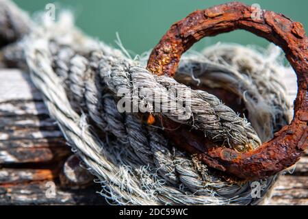 An abstract photo with selective focus of a rusted tiedown point and frayed rope on a Jetty in south australia Stock Photo