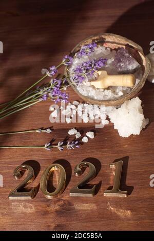 Sea salt in a coconut shell and gold metal numbers 2021 lie on a wooden surface. Stock Photo
