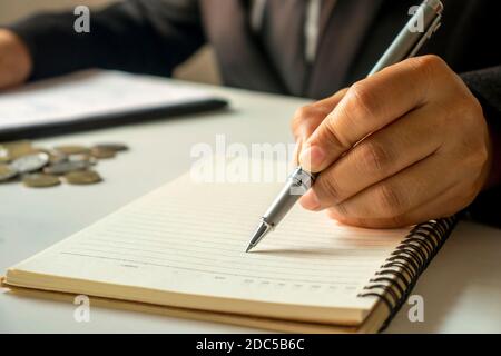 Business people take notes of income and expenses in notebook. Stock Photo