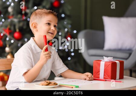 Cute little boy writing letter to Santa at home on Christmas eve Stock Photo