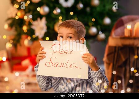 Cute little boy with letter to Santa at home on Christmas eve Stock Photo