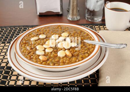 A bowl of lentil soup topped with saltine crackers Stock Photo