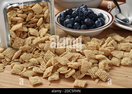 Rice squares spilling out of a glass canister, with a bowl of blueberries Stock Photo