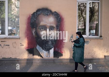 A pedestrian walks past a wall with painted image of Hovhannes Tumanyan who was an Armenian poet and is considered as the national poet of Armenia in Yerevan capital of Armenia Stock Photo