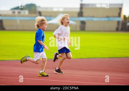 Child running in stadium. Kids run on outdoor track. Healthy sport activity for children. Little girl at athletics competition race. Stock Photo