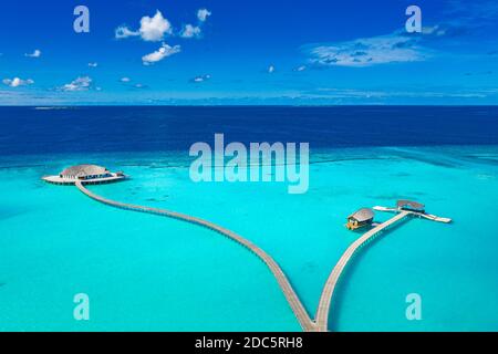 Amazing aerial landscape, Maldives island, luxury water villas resort and wooden pier. Beautiful sky and clouds and beach, summer vacation holiday