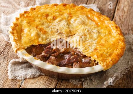 Traditional recipe of English beef steak pie with crispy puff pastry close-up in a baking dish on the table. horizontal Stock Photo