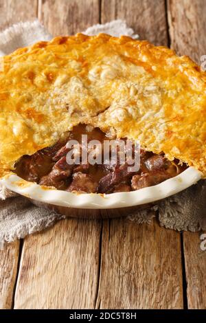 Delicious traditional English steak pie close-up in a baking dish on the table. vertical Stock Photo