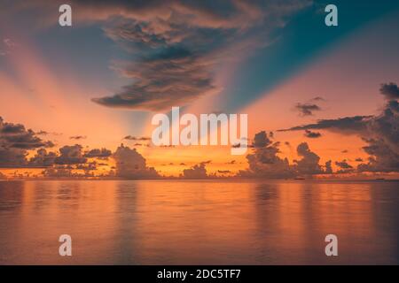 Tropical sea sunset, amazing sky reflection over endless ocean water horizon. Tranquil, relaxing seascape, sunrise, rays with clouds, colorful nature Stock Photo