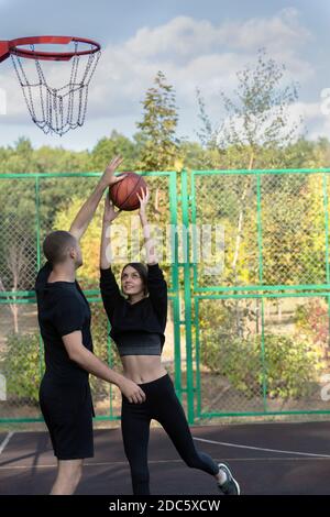 Young couple playing basketball at park basketball court Stock Photo