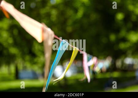 Blurred background. Multicolored triangular paper festival flags in the park. Outdoor Celebration Party. Festive mood Stock Photo