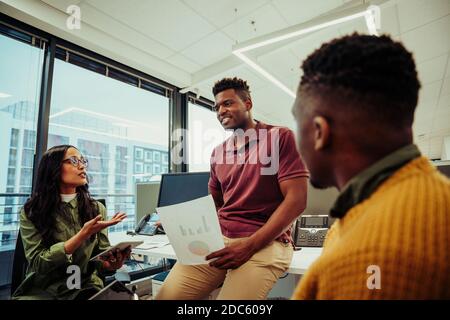 Diverse group of business entrepreneurs discussing brief of new project researching on digital tablet and through documents  Stock Photo