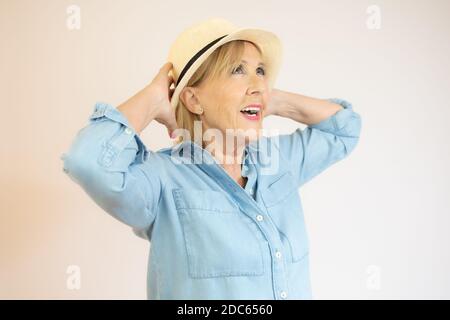 Image of senior woman smiling with short blond hair wearing straw summer hat Stock Photo
