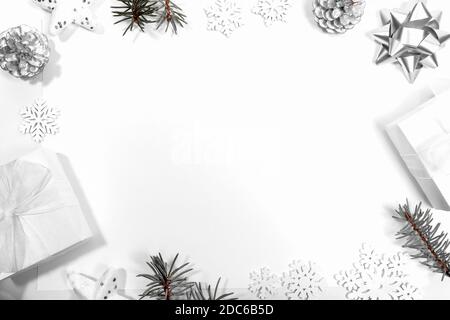 Frame made of white and silver Xmas Decorations: stars, DIY gift boxes, pine cones, snowflakes, fir branches on white. Christmas modern nordic layout. Stock Photo