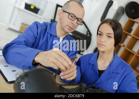 female mechanic and teacher holding car air filter Stock Photo