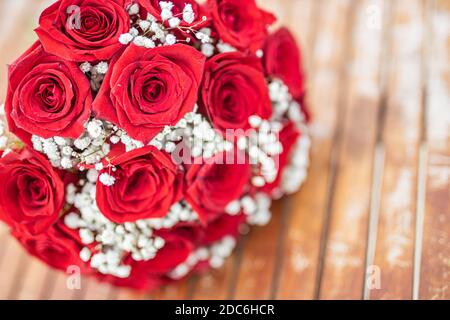 Valentines day greeting card with red roses on wooden table. Honeymoon, wedding bouquet, artistic tones. Beautiful marriage, love concept Stock Photo