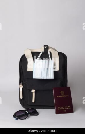 A vertical shot of black backpack with sunglasses, passport, and mask - travel concept Stock Photo