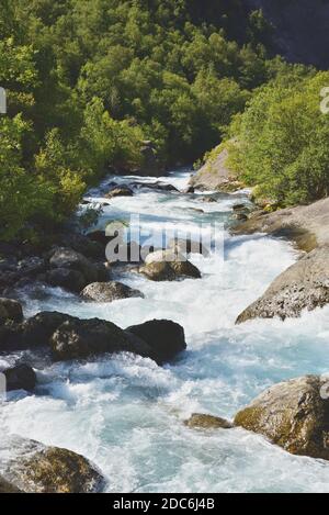 Meltwater from the Briksdal glacier flows down the valley to form the Briksdalselva River. The glacier has receded significantly in recent years. Stock Photo