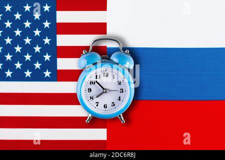 Russian and American flags and the clock as a symbol of political relations. Creative top view flat lay of Russia and USA flag alarm clock. Concept of Stock Photo