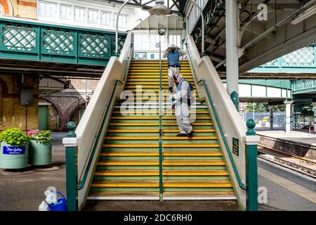 Workers In Protective Suits Clean The Holding Rails At Lewes Railway Station During The Covid 19 Pandemic, Lewes, East Sussex, UK. Stock Photo