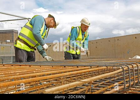 Two construction workers assemble a cage of steel reinforcement for insitu concrete on a large London building site Stock Photo