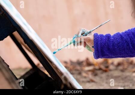 An Extinction Rebellion activist paints a message on to a hand made wooden sign at a protest camp. Dixon Clark Court, Highbury Corner. Stock Photo