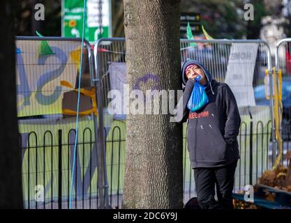 Extinction Rebellion activist leans on a mature sycamore tree at a protest camp. Dixon Clark Court, Highbury Corner. Stock Photo
